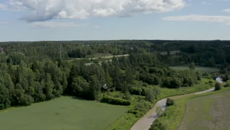 Slow-aerial-pan-of-the-countryside-in-Kerava,-Finland-with-a-motorway-and-old-stone-bridge
