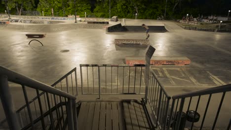 Wide-angle-from-a-staircase-of-a-skate-park-at-night-with-riders-doing-tricks-in-Montreal,-Quebec,-Canada