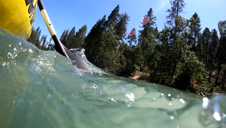 Underwater-action-footage-of-a-yellow-inflatable-kayak-with-a-black-paddle-floating-over-Bass-Lake,-California