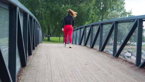 Young-girl-walking-across-a-bridge-in-a-park