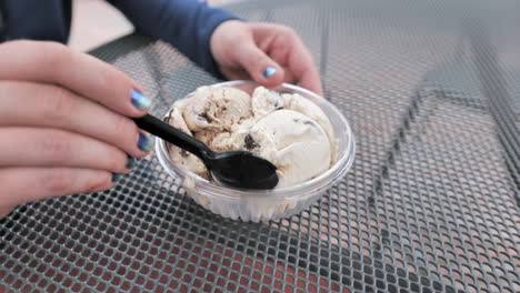 Close-up-shot-of-womans-hand-eating-ice-cream-on-metal-table