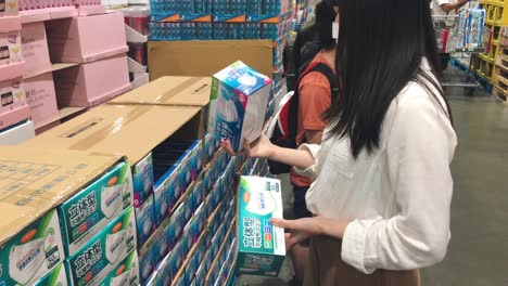 Young-Asian-Woman-Choosing-Masks-Before-Buying-During-The-Pandemic-Coronavirus-Outbreak-In-Tokyo,-Japan