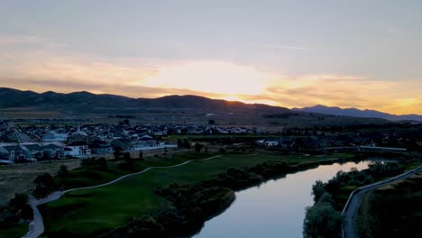 Hyperlapse-of-a-sunset-in-an-idyllic-community-along-a-golf-course-and-river-with-the-sky-reflecting-off-the-surface-of-the-river---aerial-view