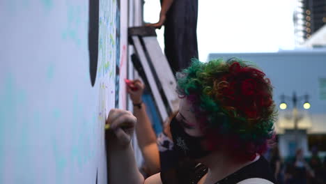 Woman-writing-message-on-wall-at-Chalk-the-Block-protest