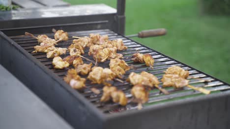 Slow-motion-shot-of-chicken-skewers-cooking-on-a-bbq-grill-outdoors