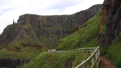 Tourists-Walking-On-Coastal-Pathway-By-The-Cliff-In-Giants-Causeway,-Northern-Ireland---long-shot