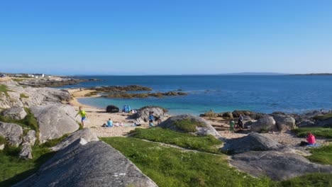 Gente-Relajándose-En-La-Orilla-De-La-Playa-De-Coral-Strand-Durante-El-Verano-En-Connemara,-Condado-De-Galway,-Irlanda