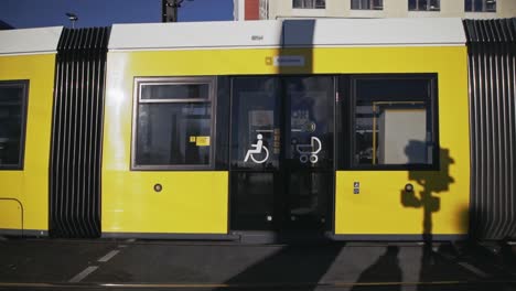 Yellow-urban-overground-passenger-train-passing-by,-slow-motion-side-shot