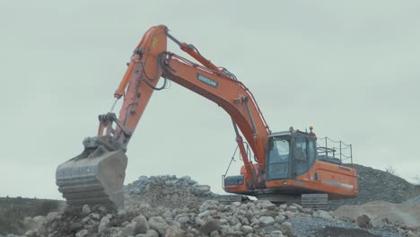 Digger-excavator-flattening-stone-in-quarry-using-old-bucket