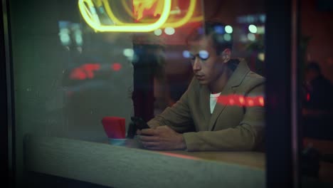 A-young-nice-looking-man-is-in-a-coffee-shop-with-a-phone