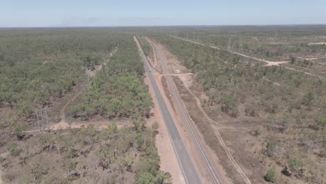 Drone-Shot-of-cars-driving-on-road-and-railway-in-Northern-Territory,-Outback-Australia