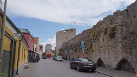 Small-street-next-to-medieval-town-wall-with-cars-and-man-riding-bike