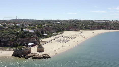 Flying-towards-the-sandy-Portimao-Beach-on-a-busy-sunny-day-in-Portugal,-Drone-Aerial-Flyover