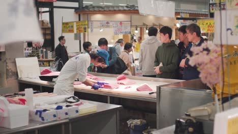 Männer-Beobachten-Den-Facharbeiter-Beim-Filetieren-Des-Fleisches-Eines-Frisch-Geschnittenen-Roten-Thunfischs-Auf-Dem-Fischmarkt-Tortore-Ichiba-In-Wakayama,-Japan