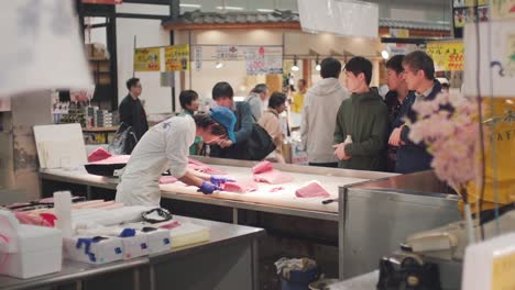 Hombres-Viendo-Al-Trabajador-Calificado-Fileteando-La-Carne-De-Un-Atún-Rojo-Recién-Cortado-En-El-Mercado-De-Pescado-Toretor-Ichiba-En-Wakayama,-Japón