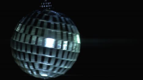 Small-rotating-disco-ball-with-reflected-moving-rays,-Anamorphic-lens-flare,-close-up-shot,-abstract-background-concept