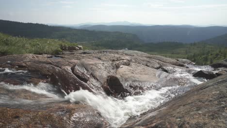 Stream-flowing-over-rocky-mountainside,-slider-closeup