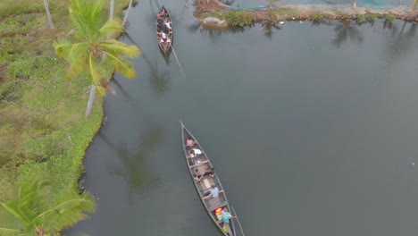 Aerial-view-of-tourists-with-their-guide-in-long-boats-exploring-the-narrow-canals-and-waterways-of-Munroe-island,-India