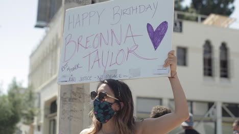 Mujer-Enmascarada-Sostiene-Cartel-De-Feliz-Cumpleaños-Para-Breonna-Taylor,-Vidas-Negras-Importan-Protesta,-Cámara-Lenta