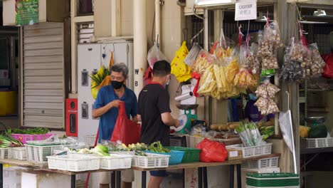 Dos-Hombres-Con-Mascarilla-Vendiendo-Frutas-En-El-Puesto,-Toa-Payoh