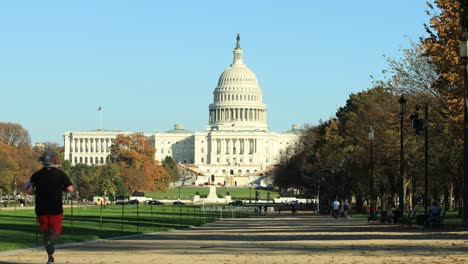 People-walking-and-jogging-in-park-in-front-of-Capitol-building-in-autumn