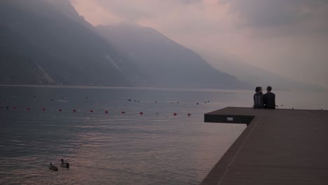 La-Pareja-Disfruta-Juntos-Del-Amanecer-Romántico,-La-Impresionante-Vista-De-La-Montaña,-El-Lago-De-Garda