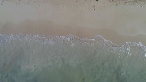 Splash-of-waves-on-a-beach-in-the-Dominican-Republic,-with-white-sand,-shot-with-drone