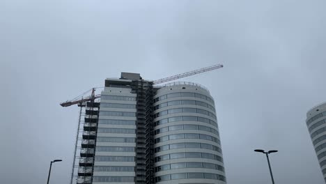 Wide-shot-of-spinning-crane-over-new-modern-hospital-during-cloudy-day-in-Muenster,Germany