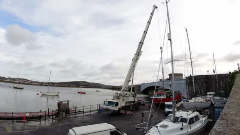 Hydraulisches-Teleskopkranfahrzeug,-Das-Fischerbootschiff-In-Conwy-Hafenwasserzeitraffer-Hebt