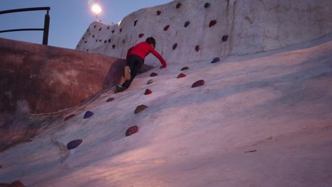 Kid-having-lots-of-fun-on-a-beautifull-october-dusk-climbing-boulders-on-a-climbing-wall-at-Jamadi-Park