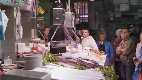 A-view-of-consumers-at-the-meat-shop-of-Mercat-Central-located-across-from-the-Llotja-de-la-Seda-and-the-church-of-the-Juanes-in-central-Valencia,-Spain