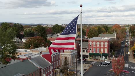 Close-up-of-American-Flag-flying-above-small-town-in-USA
