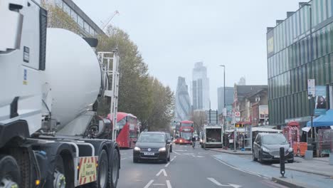 Cars-and-buses-driving-down-London-Whitechapel-road-with-city-centre-in-background-tight