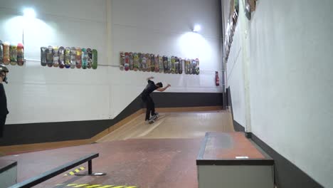 Professioneller-Skater-Springt-Mit-Kickflip-Flip-Trick-An-Bord-In-Der-Indoor-Skatehalle