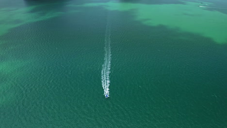 drone-tilting-down-on-driving-longtail-boat-on-wide-ocean-scenery,-aerial