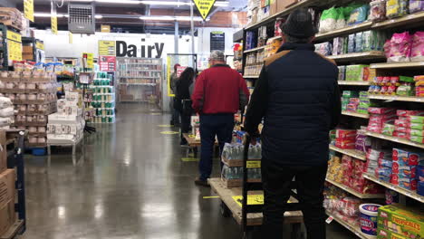 Customers-In-Queue-With-Social-Distancing-Inside-Cash-And-Carry-Store-In-Coos-Bay,-Oregon---Coronavirus-Health-Protocol---panning-shot