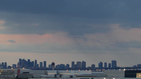 Time-lapse-of-a-city-skyline-with-skyscraper-buildings-at-the-horizon-at-sunset,-wide-shot