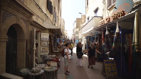 Turistas-Caminando-Y-Mirando-Las-Tiendas-De-Souvenirs-En-Essaouira,-Marruecos