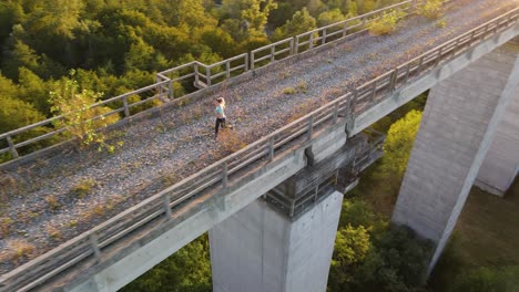 Girl-jogging-on-bridge-at-sunset-in-4k,-drone-shot