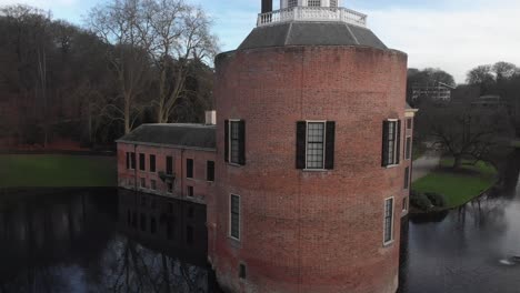 Aerial-sideways-pan-around-rook-tower-of-Rosendael-castle-with-barren-winter-trees-in-the-background