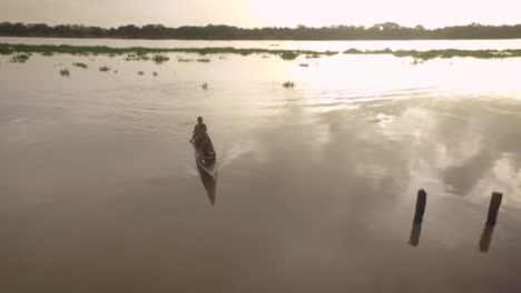 Vista-Aérea-De-Una-Pequeña-Canoa-Indígena-Cruzando-El-Río-Orinoco-Durante-La-Puesta-De-Sol