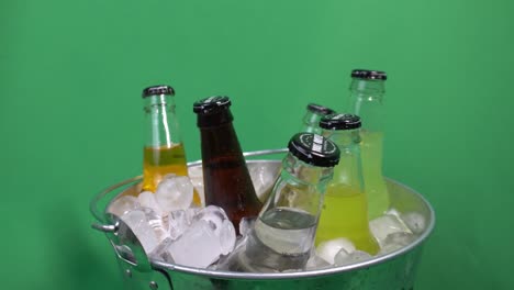 1-2-Insel-Soda-Getränke-Sortierte-Flaschen-Fruchtige-Kohlensäurehaltige-Getränke,-Die-Sich-In-Einem-Mit-Eis-Gefüllten-Getränkeeimer-Mit-Grünem-Hintergrund-Drehen