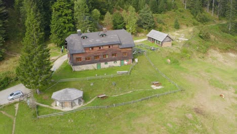 Aerial-pull-back-shot-of-a-wooden-house-in-a-mountain-at-Sostanj