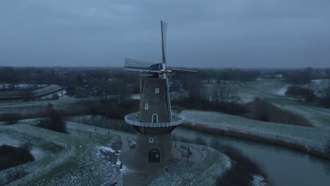 Aerial-View-Of-Nooit-Volmaakt-Flour-Mill-On-The-Bank-Of-Linge-River-In-Wintertime-At-Gorinchem,-Netherlands