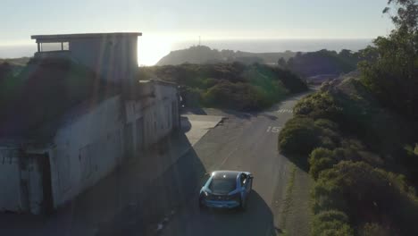 Aerial-view-of-blue-hybrid-BMW-i8-driving-Marin-Headlands-coastal-road
