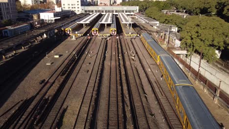 Luftaufnahme-Des-Gelben-Zuges,-Der-Bei-Sonnenlicht-Am-Bahnhof-Lacroze-In-Buenos-Aires-Ankommt---Kamerafahrt