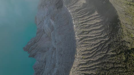 Vulkankraterkammwand-Mit-Erosionslinien-Und-Blauem-Saurem-Wassersee,-Unfruchtbares-Gelände