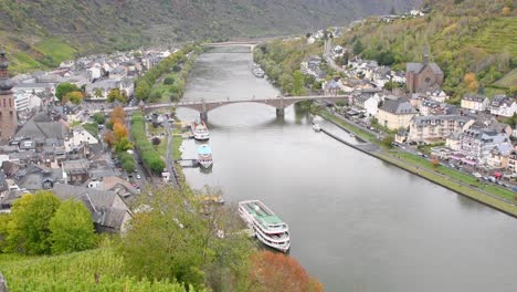 Top-down-shot-of-rhine-river-with-docking-tourism-ship-and-small-village-connecting-with-bridge