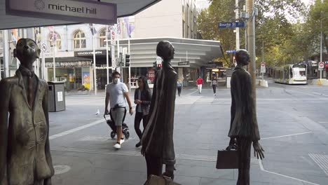 Personas-Con-Máscaras-Caminan-Por-Las-Calles-Tranquilas-De-Melbourne,-Pasando-Estatuas-Populares-Durante-El-Cierre-Del-Coronavirus-covid-19---Melbourne,-Australia