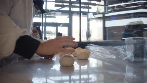 Chef-forms-pizza-pieces-on-restaurant-kitchen-table